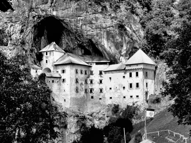 Predjama Castle, Slovenia. <small>-The castle was once the fief of a robber-barron who would taunt those besieging the castle by sending down fresh fruit to his enemies. This fruit was delivered through a network of secret caves above the fortress. A traitor, paid off by the enemy, advised those laying siege to Predjama that there is one place that even a King must go on foot, alone. When the laird went to the, you know, the <i>the</i> in the middle of the night, the traitor made a signal to the enemies who blasted the smallest room with cannon fire, killing the barron.</small>